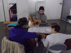 Vincent Pouply professeur de guitare donnant un cours de guitare à des jeunes élèves chez Imagina Music
